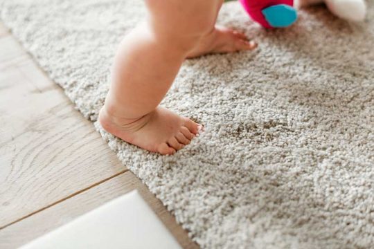 Baby standing on clean carpet